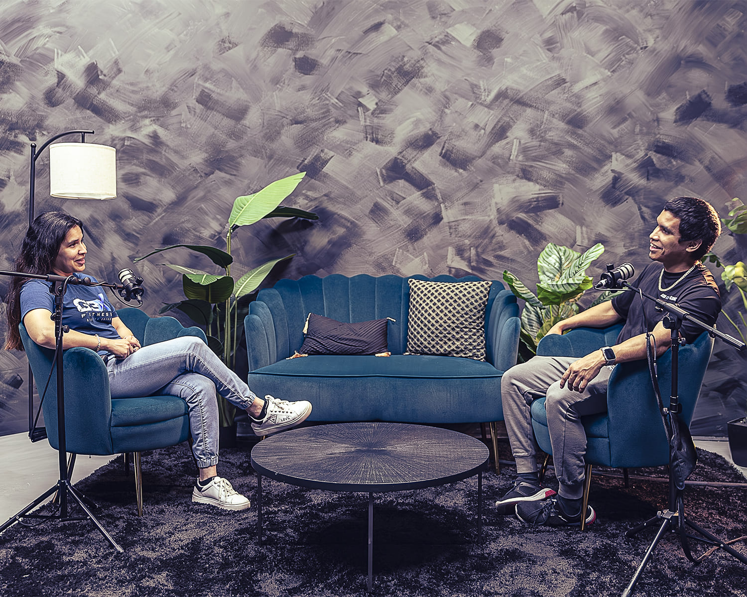 Two people sitting in a modern room with blue furniture and plants for The G3X Podcast