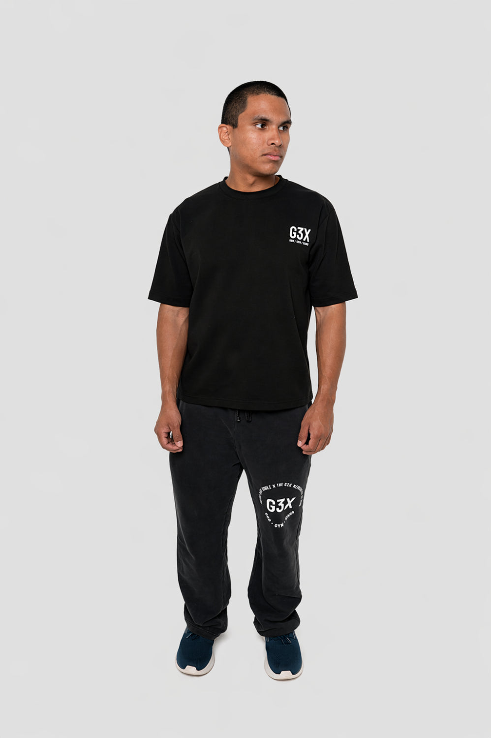 Man wearing a black G3X Fitness t-shirt and black pants with a G3X Fitness logo on a light gray background