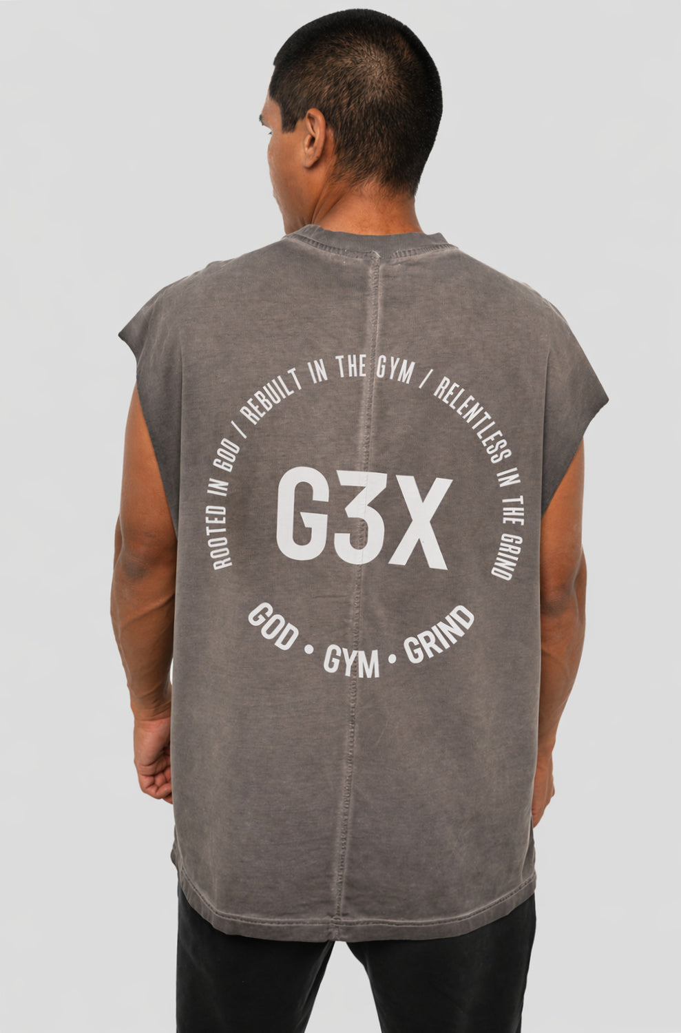Person wearing a sleeveless gray shirt with 'G3X' branding on the back against a white background