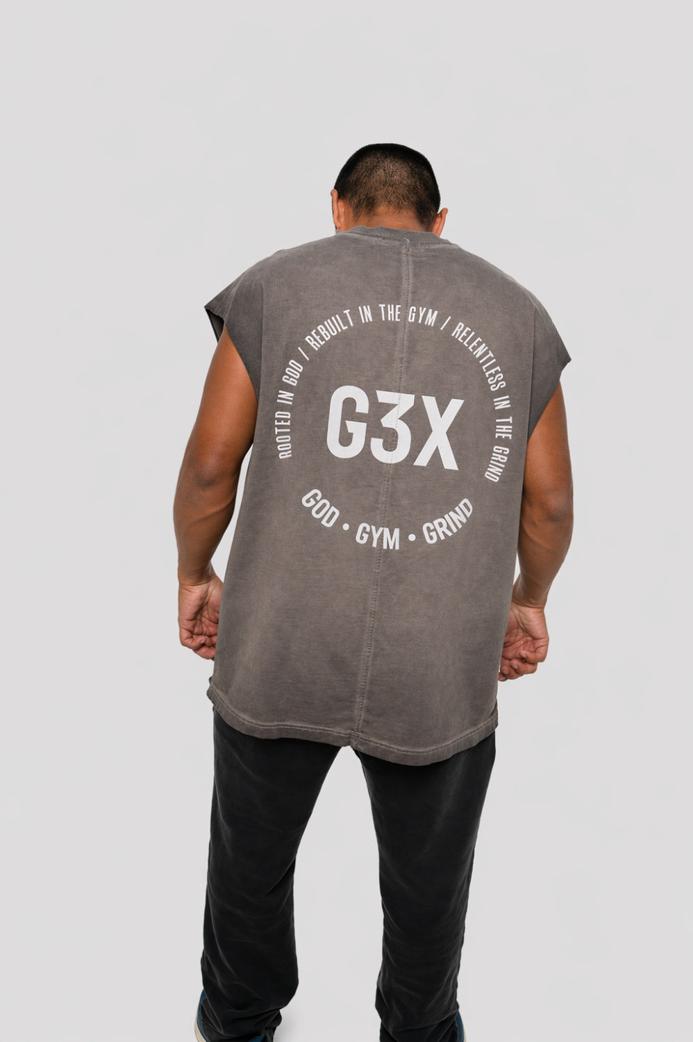 Person wearing a gray sleeveless shirt with 'G3X' branding on the back against a white background