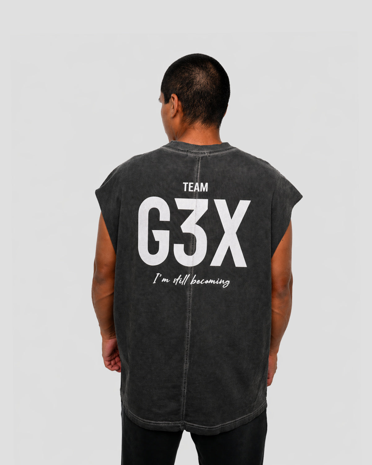 Person wearing a sleeveless black shirt with 'Team G3X' text on the back against a gray background