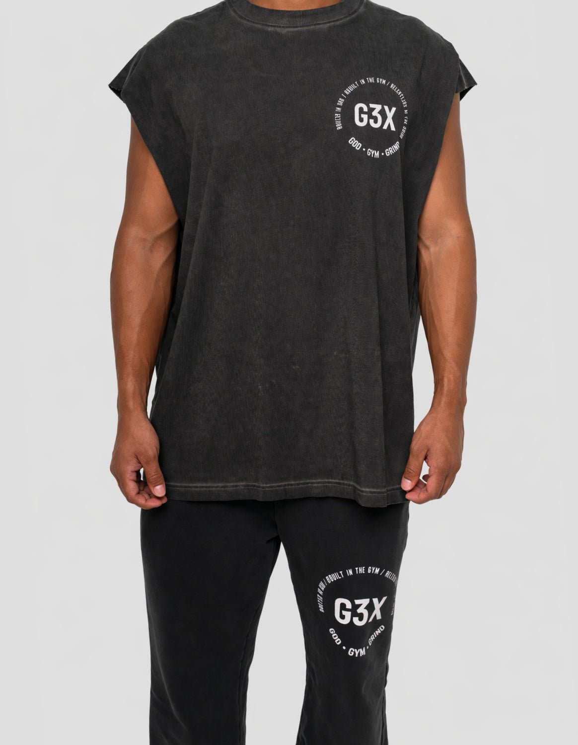 Person wearing a black sleeveless shirt and pants with 'G3X' branding on a background
