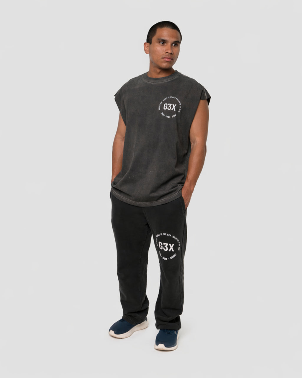 Person wearing a black sleeveless shirt and black pants with '63X' branding on a light background